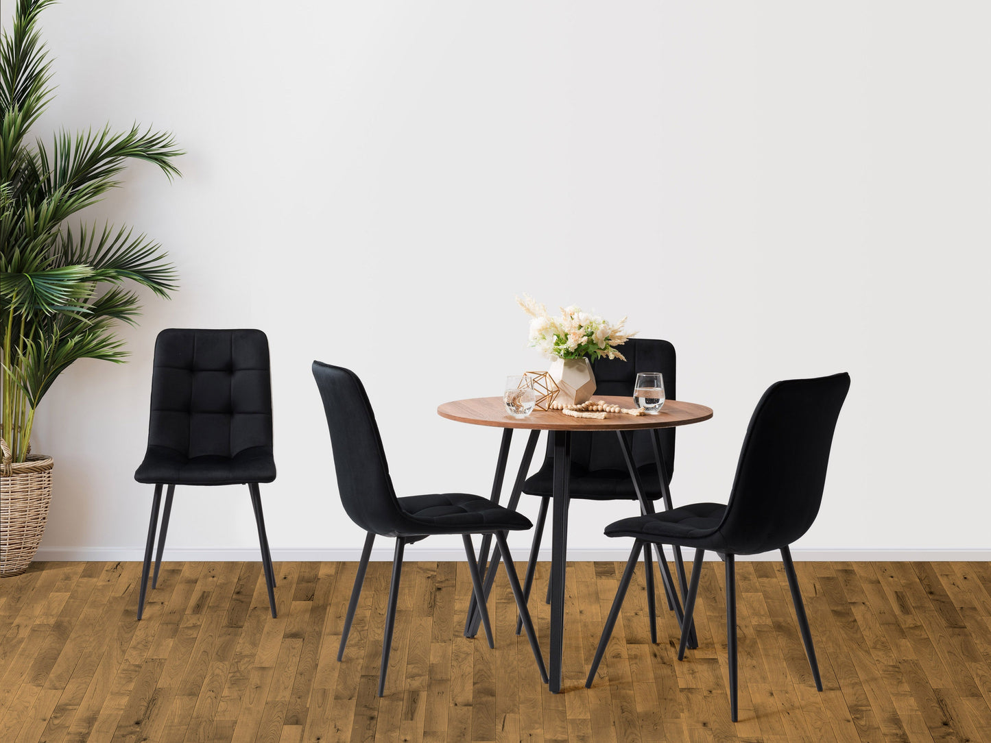 Black round dining table set with four cushioned chairs, sleek metal legs, and a modern design perfect for contemporary dining rooms. The table features a smooth black finish and sturdy construction.