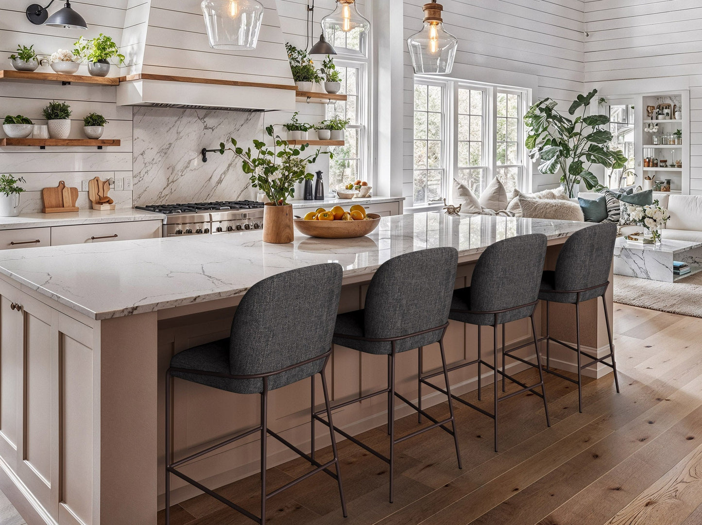 Modern bar stool with a sleek black metal frame, cushioned seat in light gray fabric, and a footrest, set against a minimalist kitchen island with wooden cabinetry and marble countertop.