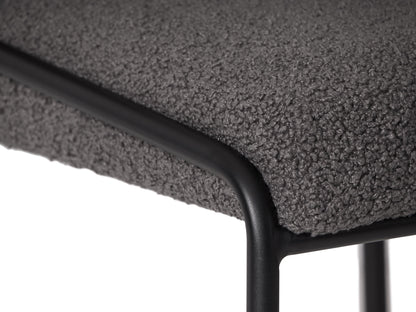 Grey boucle bar stool with plush texture, featuring a curved backrest, black metal legs, and footrest, perfect for modern kitchens and home bars.