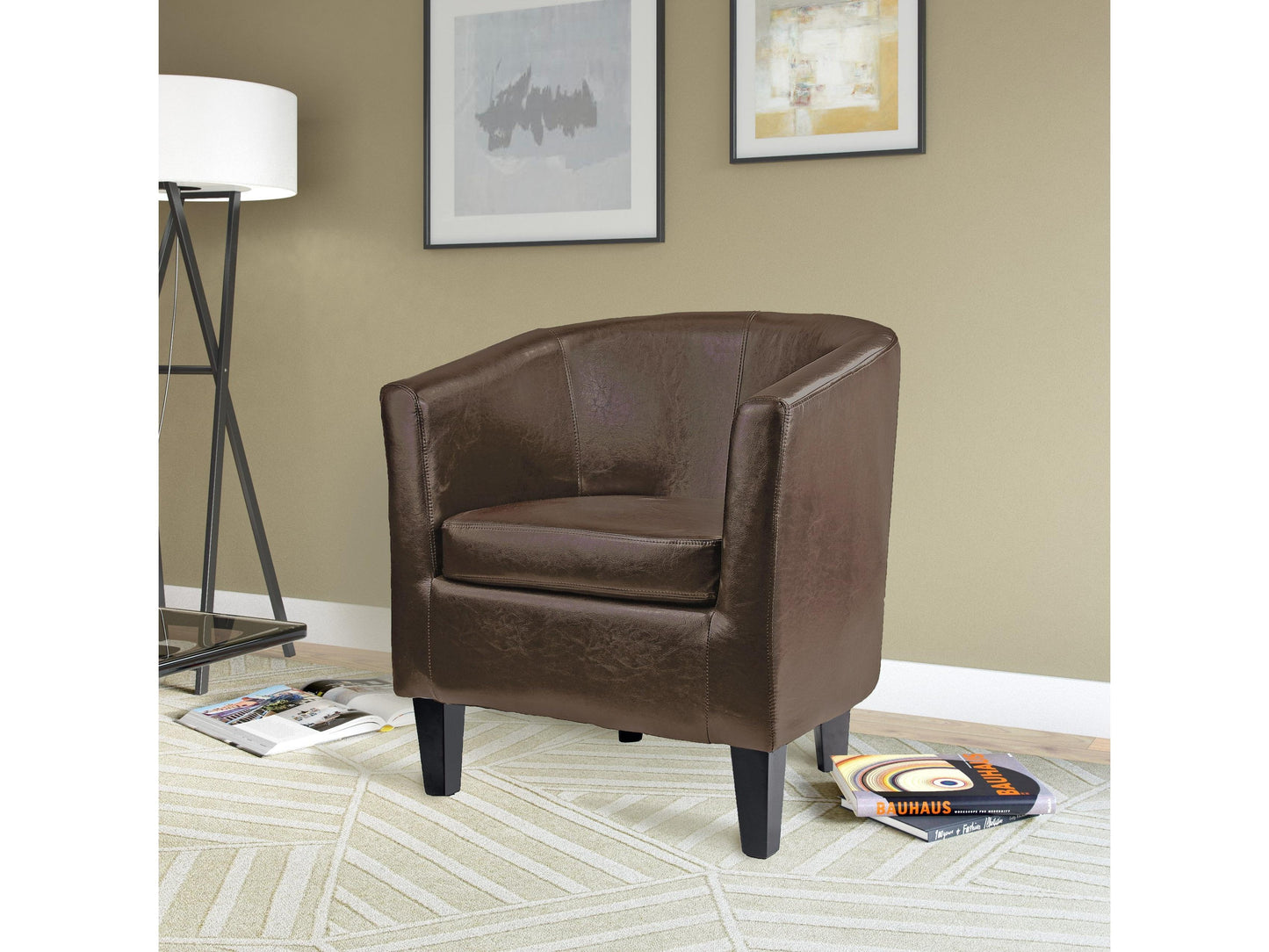 Brown leather barrel accent chair with tufted backrest, black wooden legs, and brass nailhead trim. Ideal for living rooms or offices, offering a blend of classic and modern design.