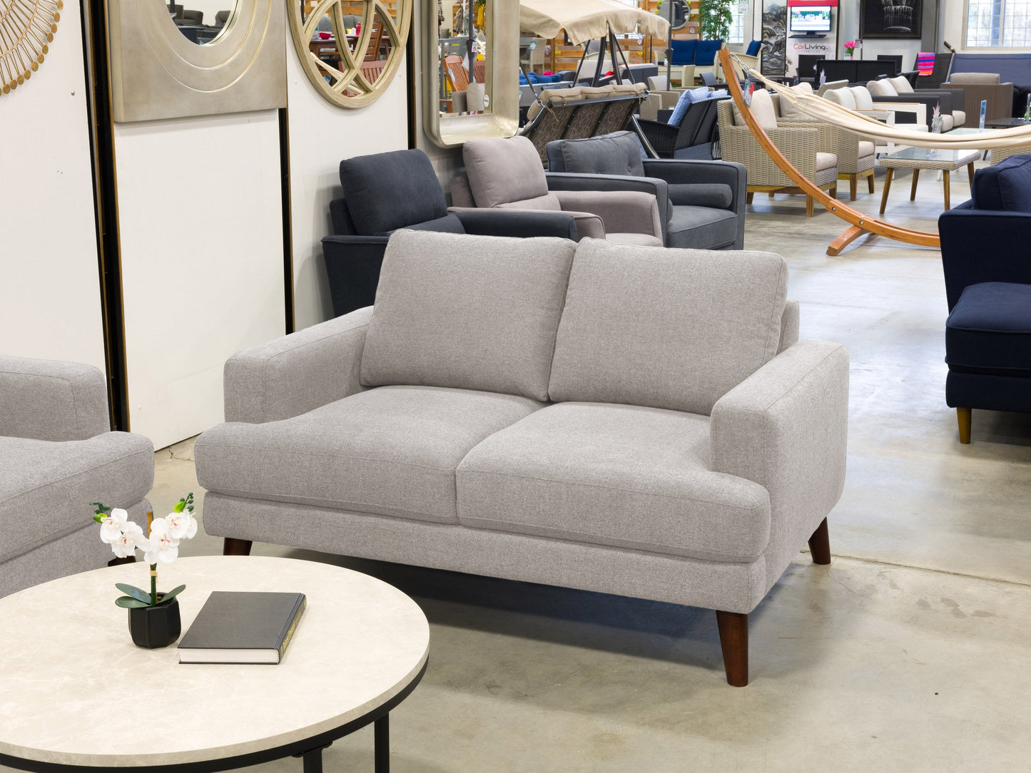 Light grey modern loveseat with sleek lines, plush cushions, and wooden legs, perfect for contemporary living rooms. Upholstered in soft, durable fabric for comfort and style.