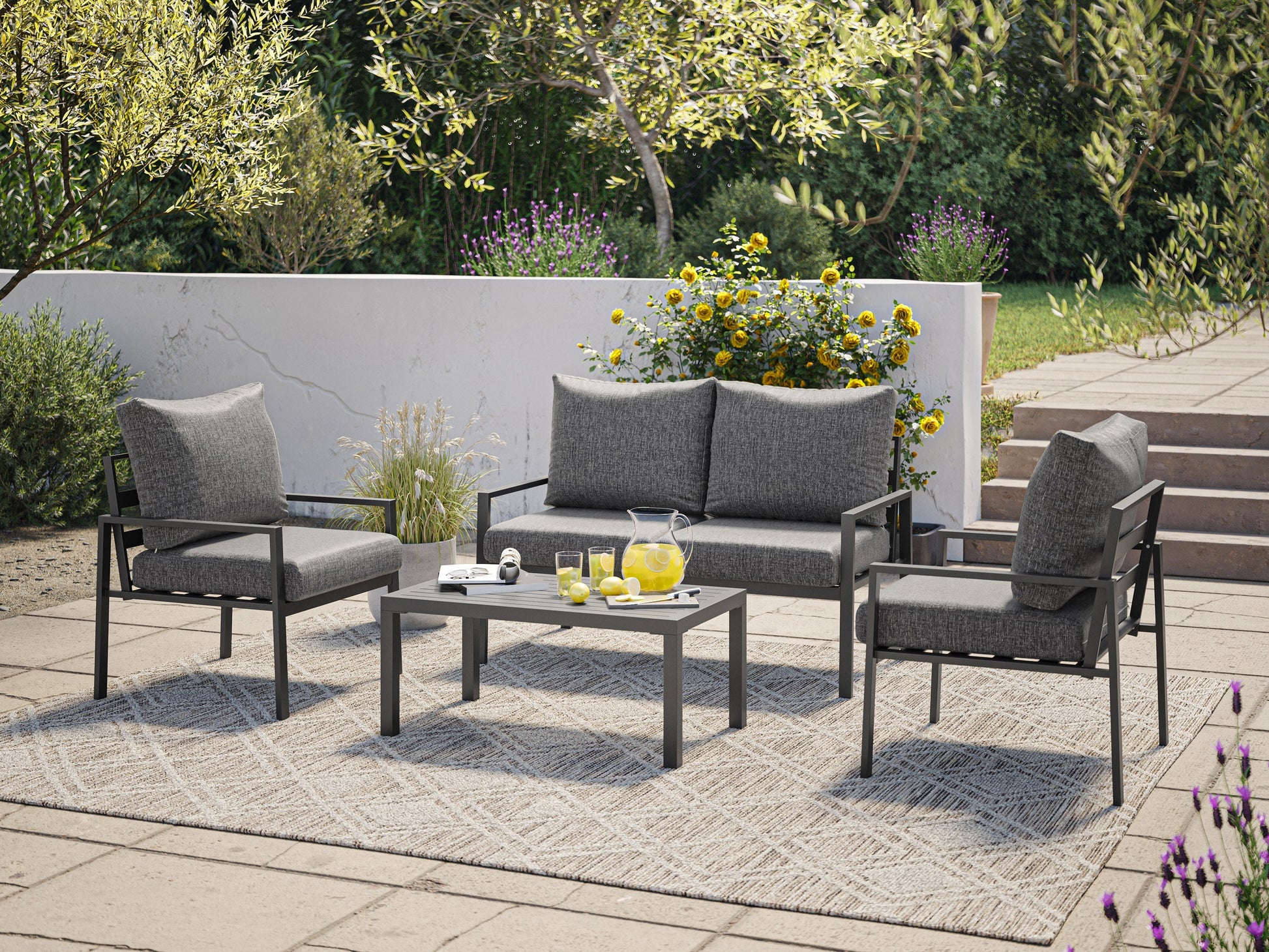 Grey deluxe 4-piece patio conversation set with cushioned seats, including a loveseat, two armchairs, and a glass-top coffee table, featuring weather-resistant wicker and sleek metal frames for outdoor use.