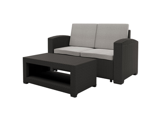 Outdoor wicker loveseat with light brown rattan frame, cream cushions, and dark brown accent pillows. Features weather-resistant materials, comfortable seating for two, and a sleek design perfect for patio or garden.