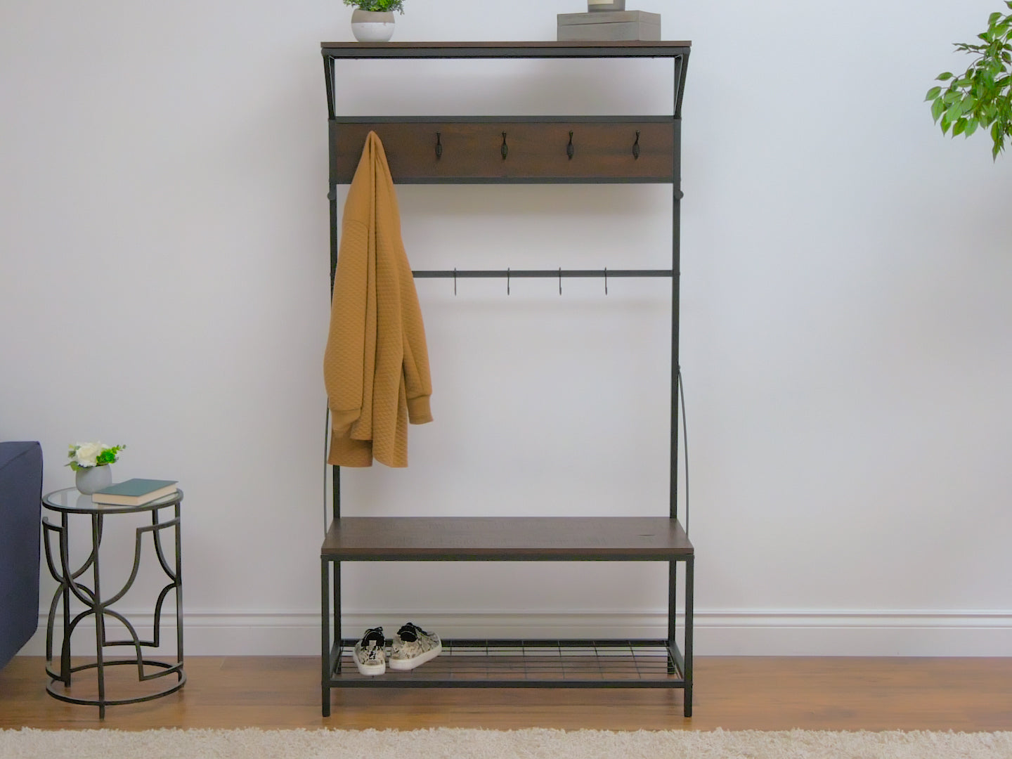 Modern hall tree with storage bench in rustic brown wood finish, featuring metal hooks for hanging coats, a cushioned seat, and spacious lower storage for shoes and accessories.